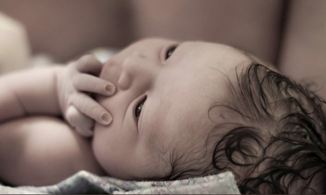 Newborn with eyes open and hand to mouth. Newborn with eyes open and hand to mouth.