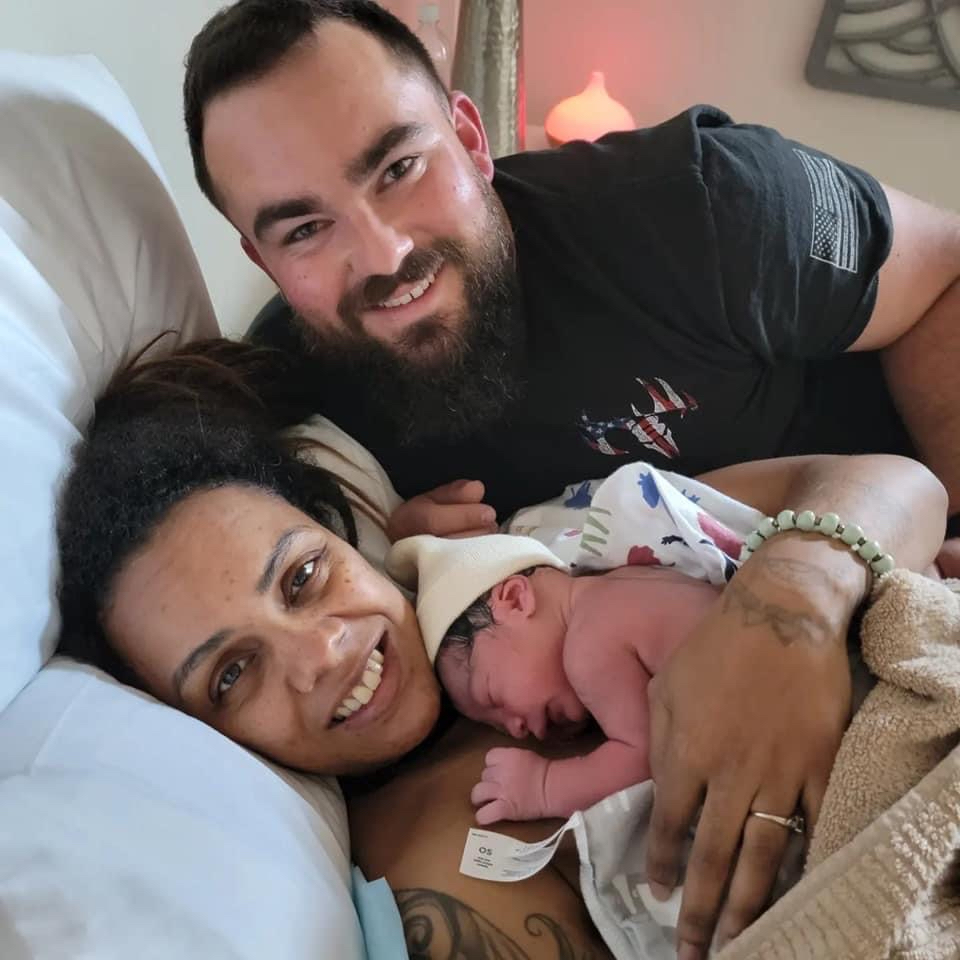 Happy Family Smiling parents with newborn baby in warming cap.