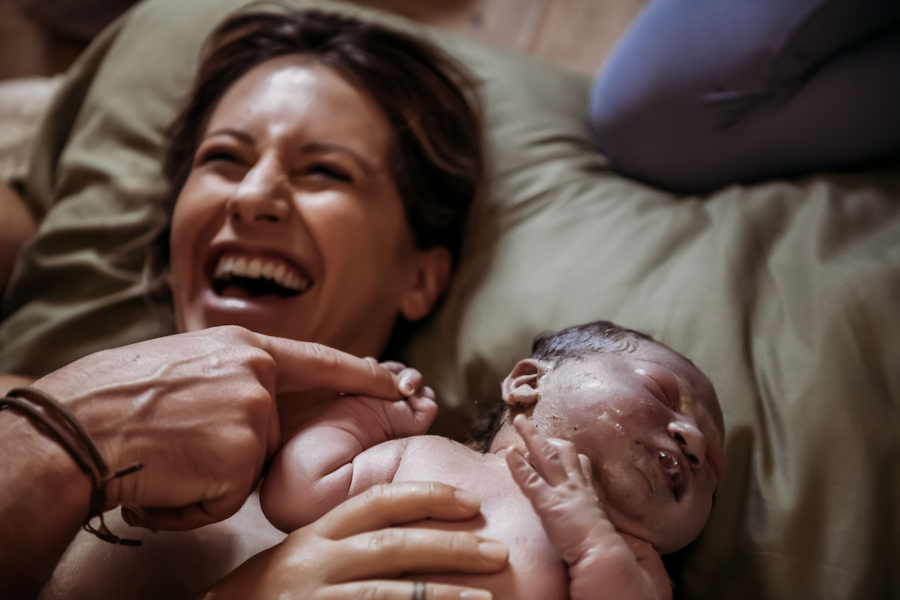 Joy of Natural Childbirth Elated mom holding newborn.